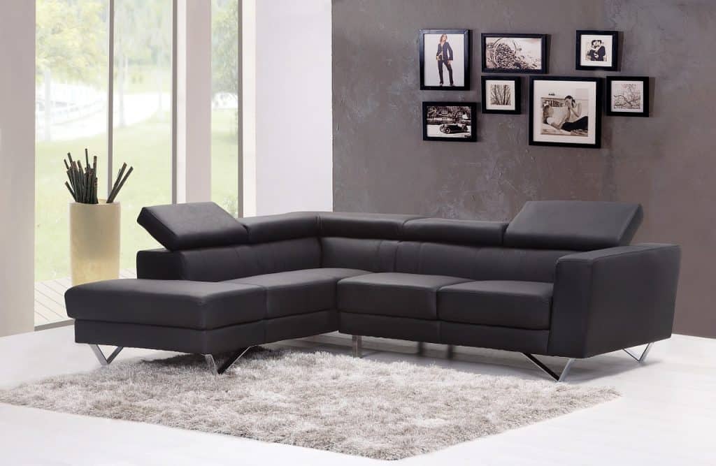 Modern living room interior with pictures on gray wall and dark gray corner sofa
