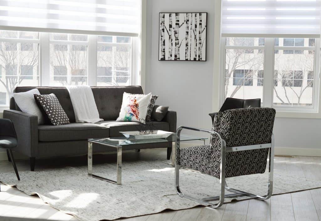 Living room interior with a dark gray sofa, glass coffee table and accent chair