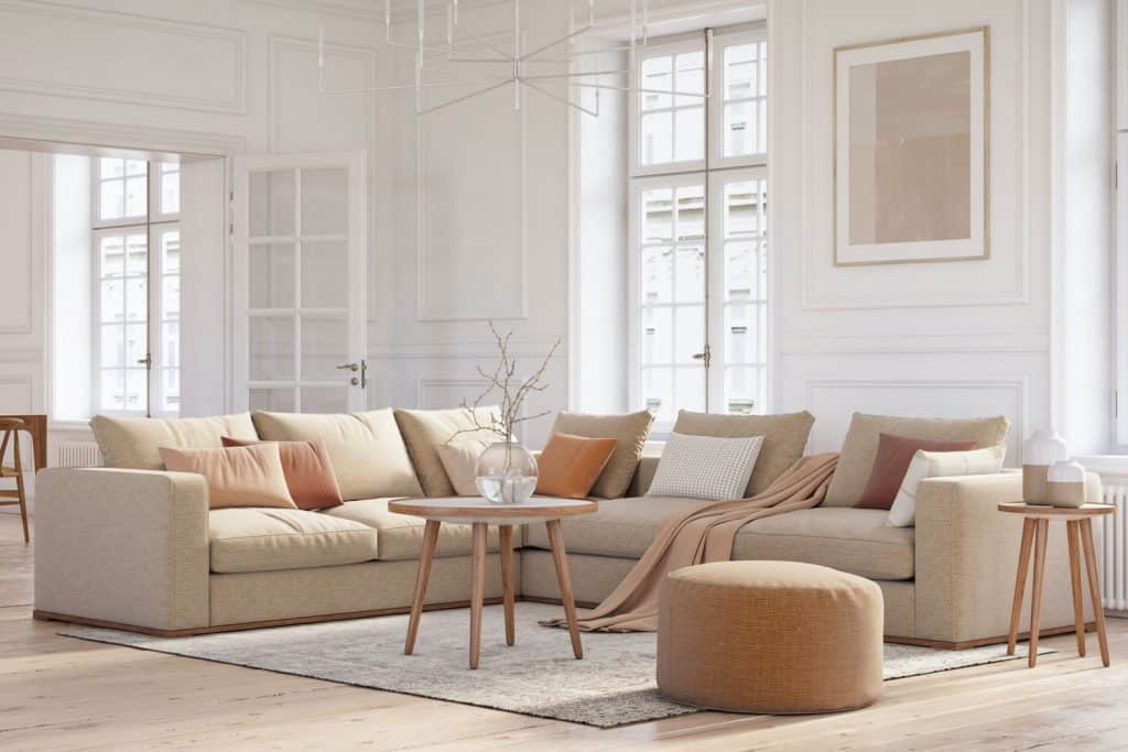 A white wall living room with a beige sectional sofa with beige throw pillows inside a white wall living room 