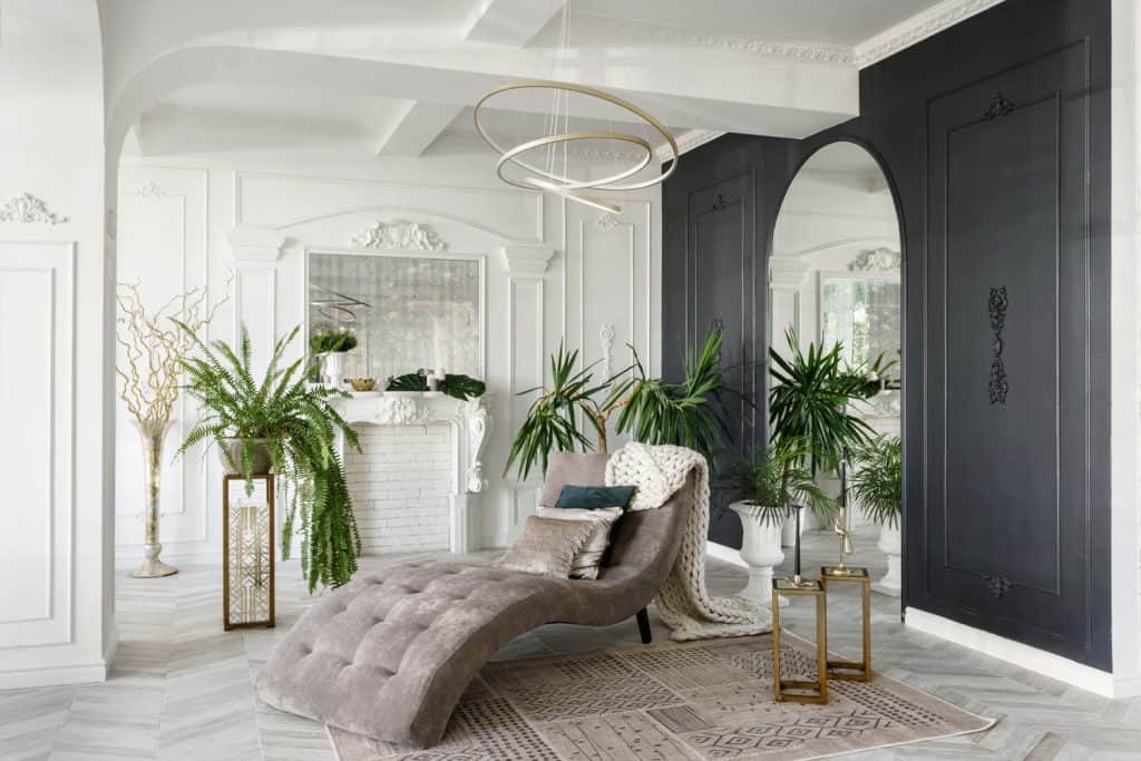 Modern Scandinavian inspired white living room with lots of indoor palm trees, and a long relaxing chair 