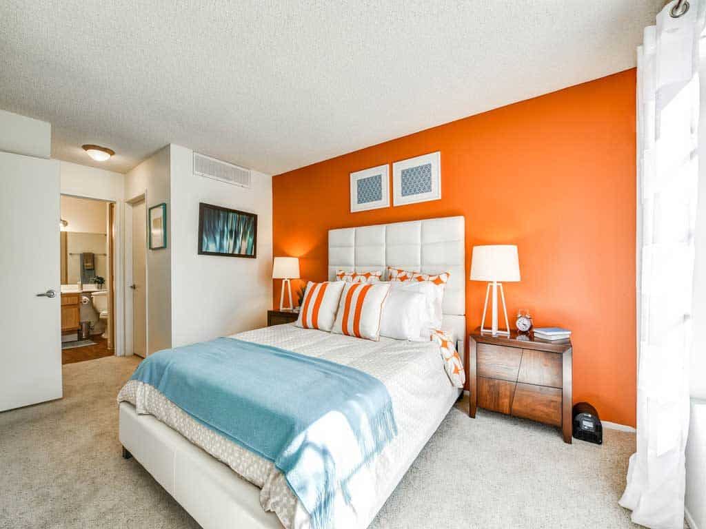 A white themed bedroom white painted wall and an orange accent wall