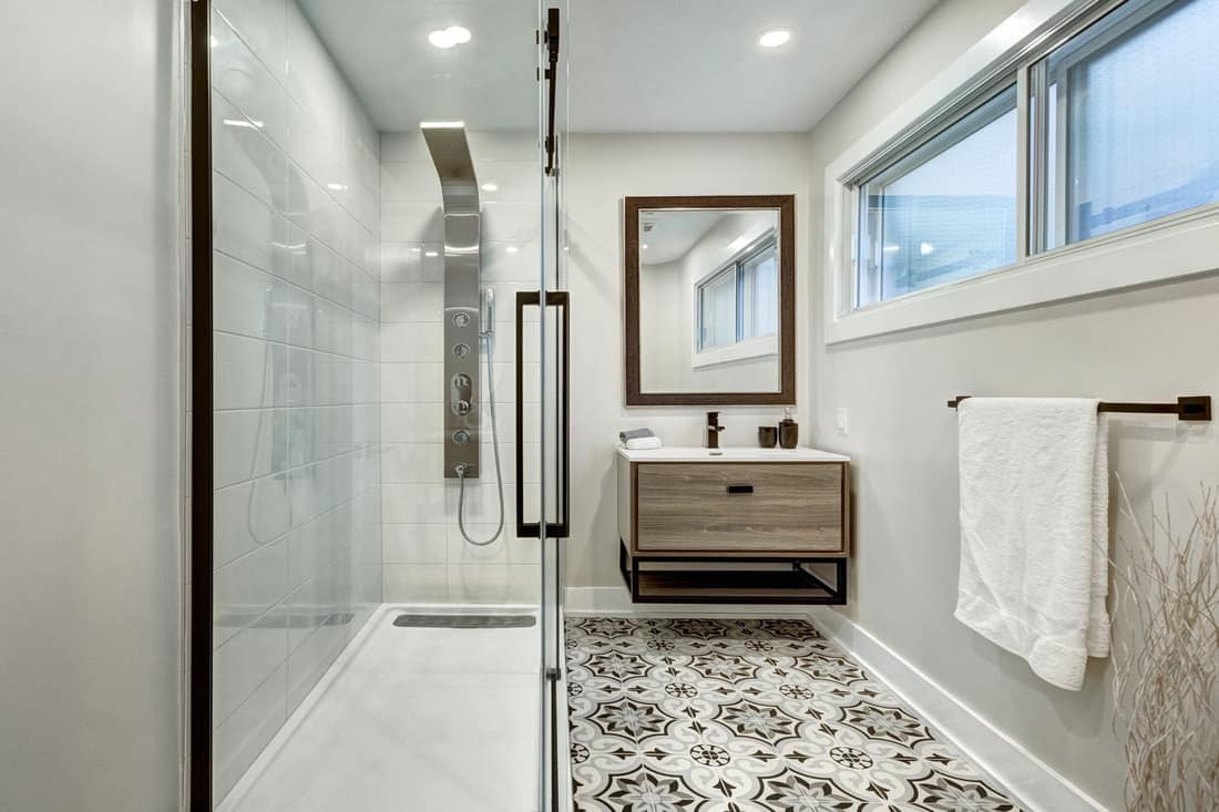Interior of a modern Canadian contemporary themed bathroom with a decorative tile flooring, and glass wall shower area