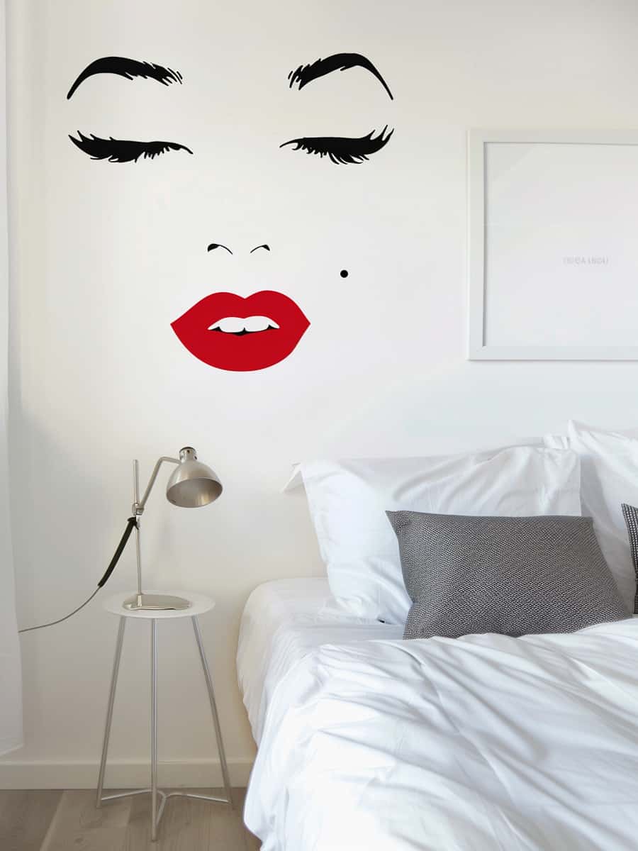A striking Marilyn Monroe-inspired decal featuring her signature black cat eye and red lips, elegantly adorning a clean, white wall in the bedroom