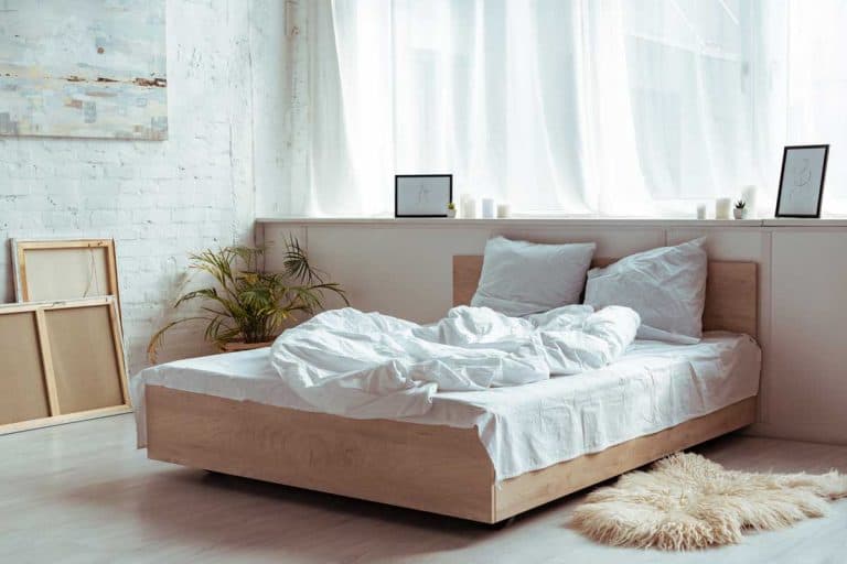 A modern bedroom with wooden bed, white sheets and pillow, Do Bedrooms Need Windows (And 10 SOLUTIONS for When They Don't)