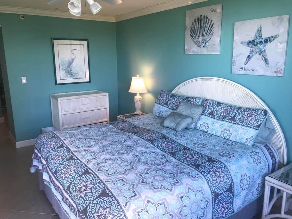 Small narrow bedroom with teal painted walls and a floral bedding