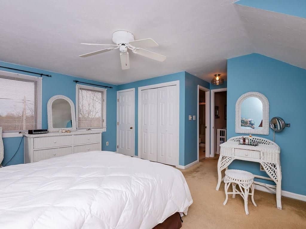 Spacious teal painted living room with white bedding and furnitures