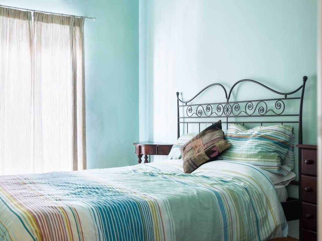Small teal living room with bedroom with a teal painted wall and teal beddings
