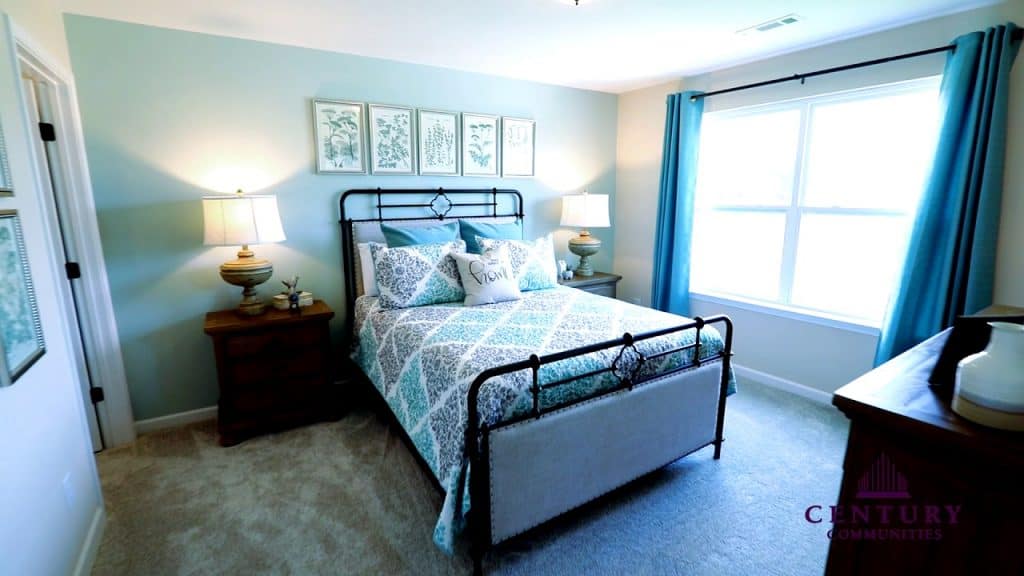 Spacious interior of a modern bedroom with a metal framed bed and teal curtains on the wall