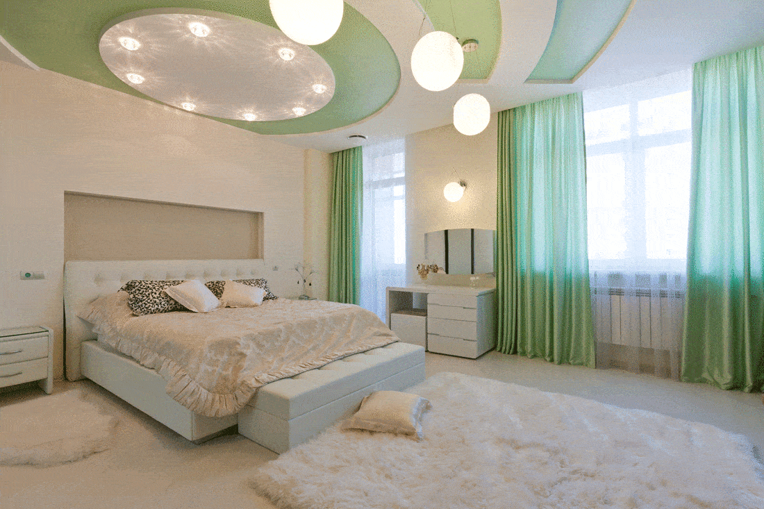 Beautiful modern apartment interior with white bed and green curtains