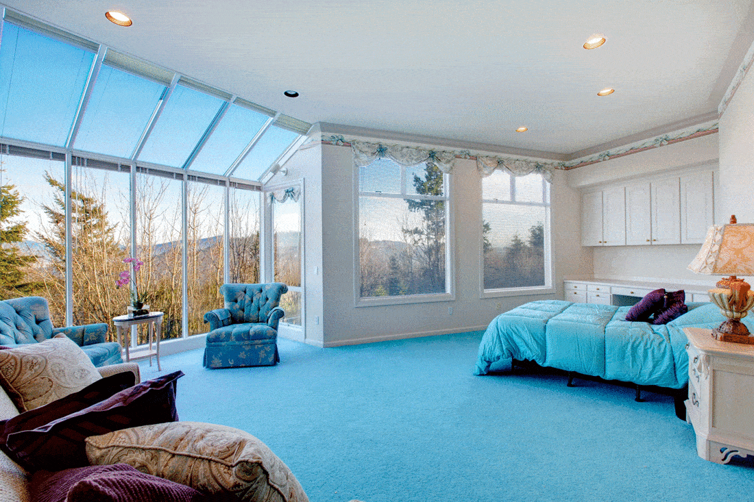 Great design for bedroom with glass wall. Blue carpet floor well matched with light blue bedding and white wood storage cabinets