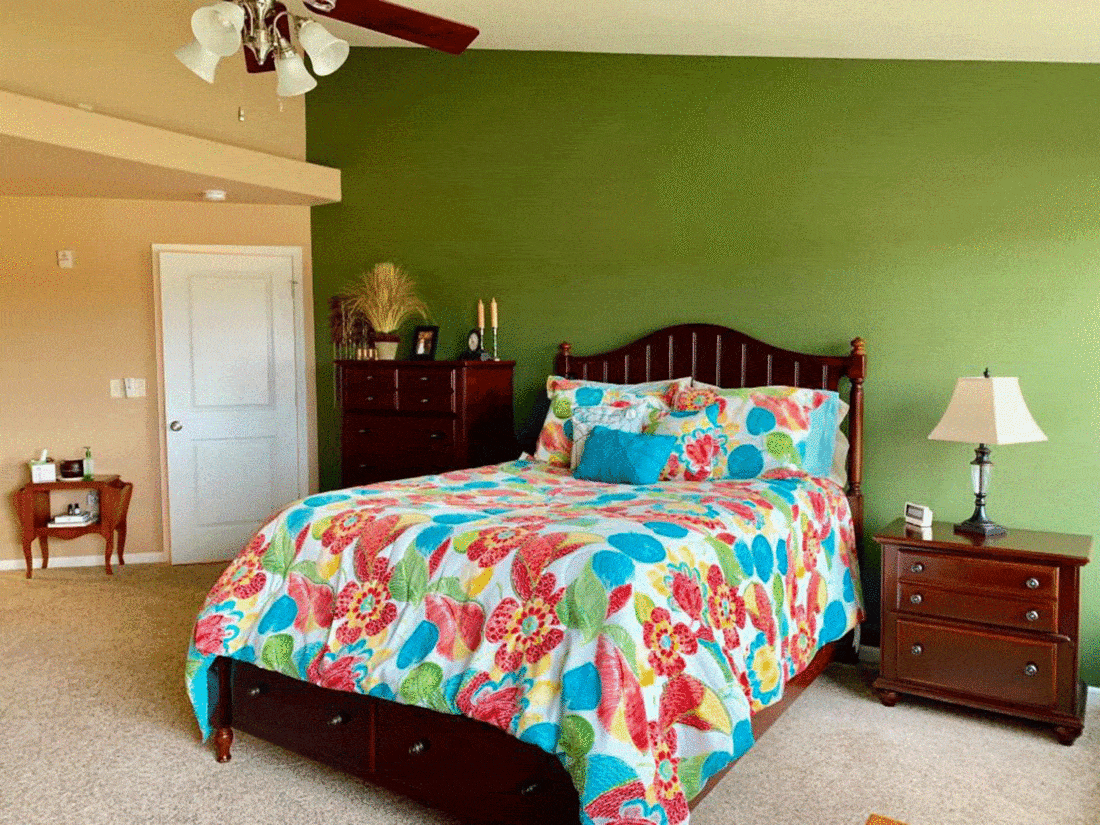 Green bedroom with colorful flower sheets