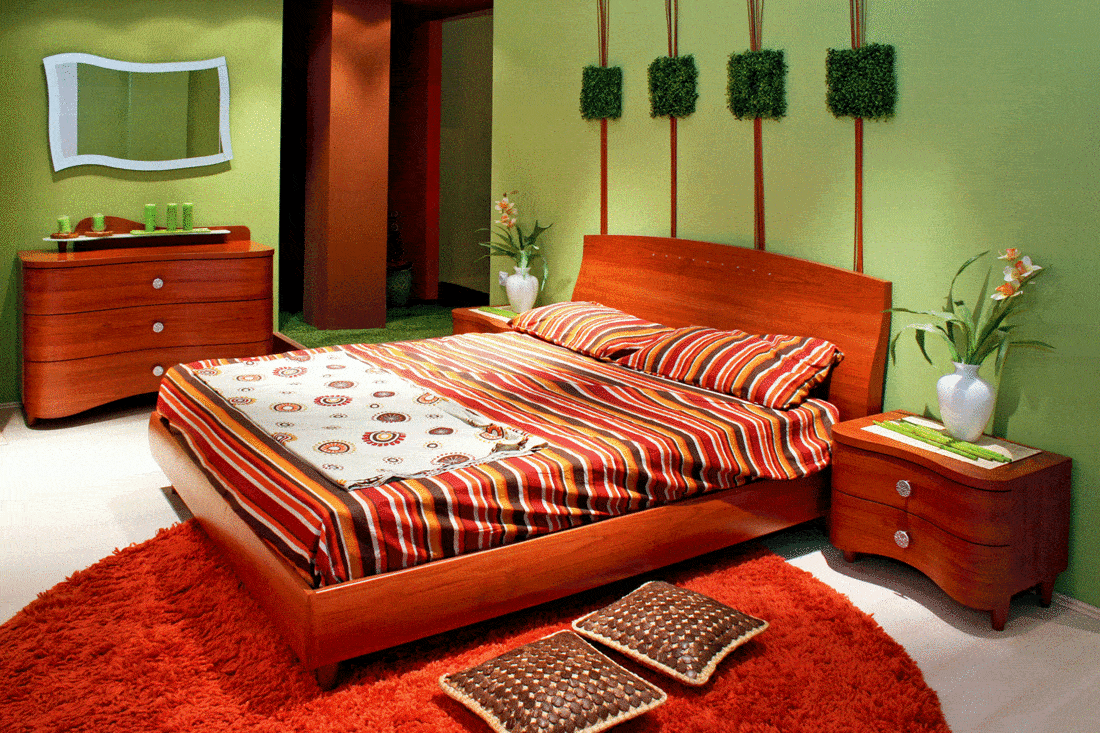 Green wall bedroom with big red wooden double bed