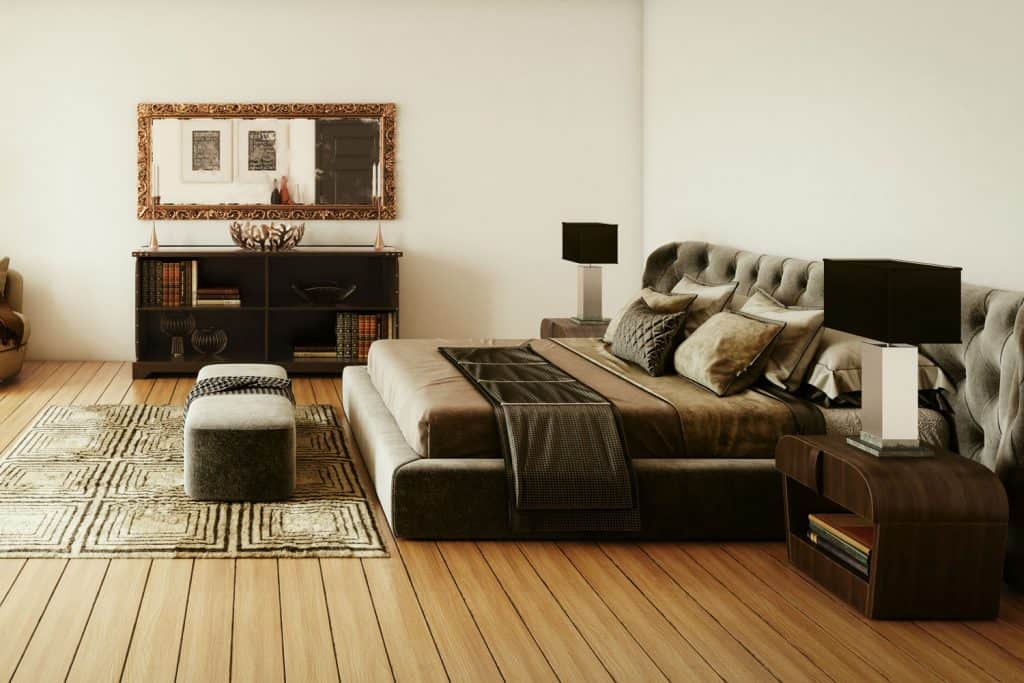 Interior of a modern dark themed bedroom with ottomans placed right on the foot of the bed