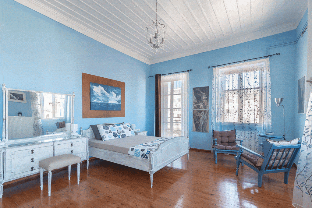 Light blue themed large master bedroom with wooden carpet flooring