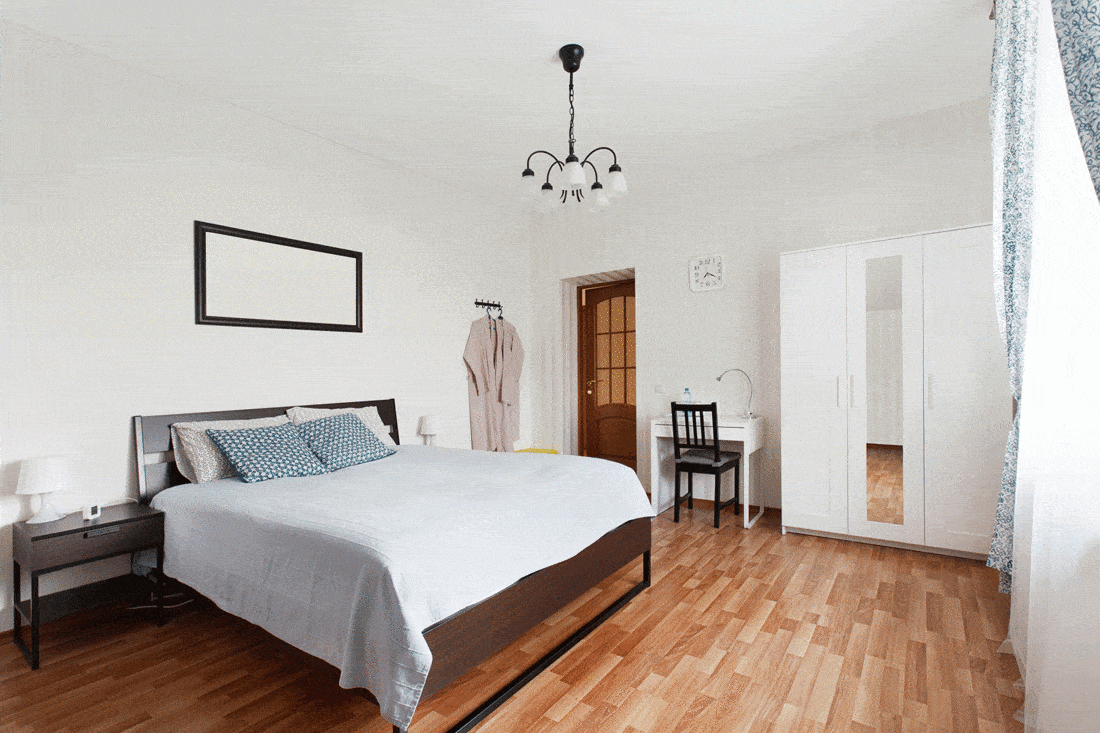 Modern bedroom with white interior and wood flooring