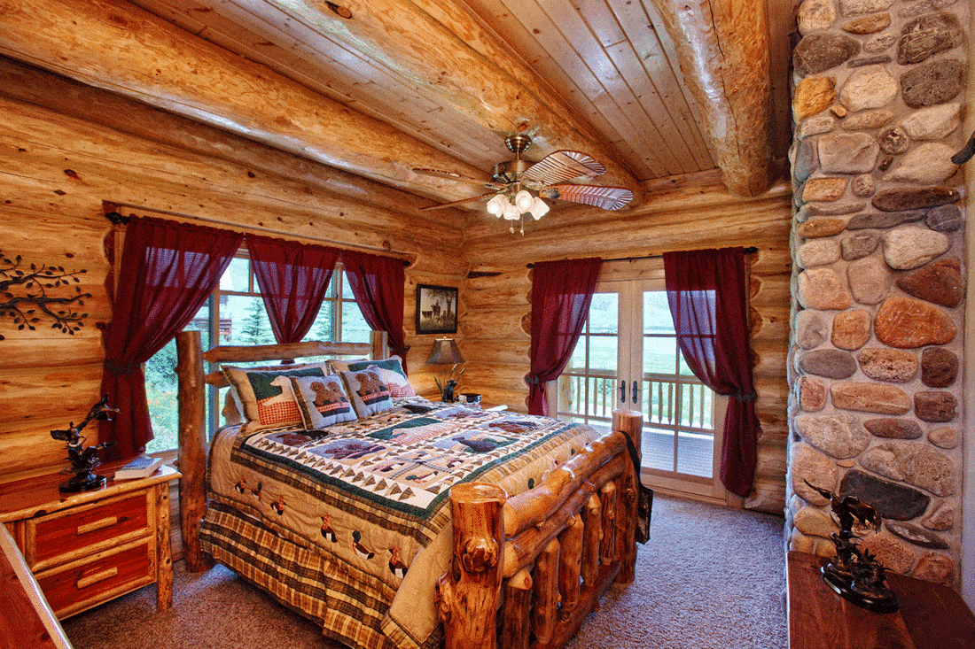 The interior of a bedroom in a modern yet rustic log cabin in the mountains