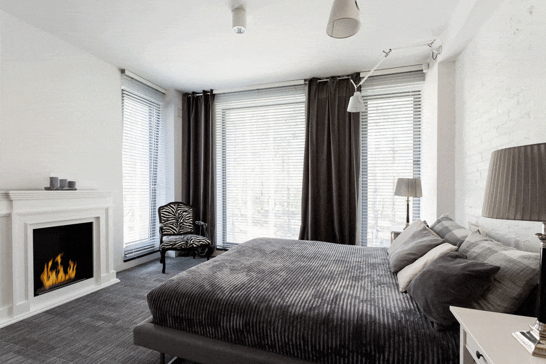 White and grey master bedroom with fireplace, large windows and double bed
