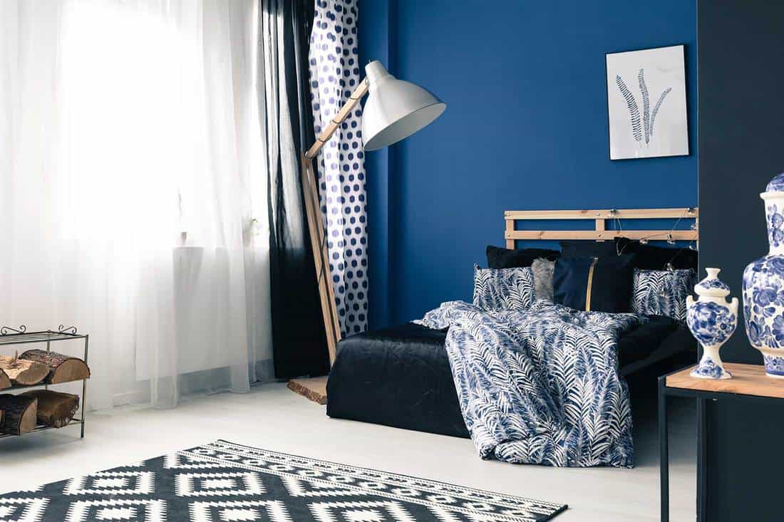 Calming navy blue and white themed bedroom with wooden bed