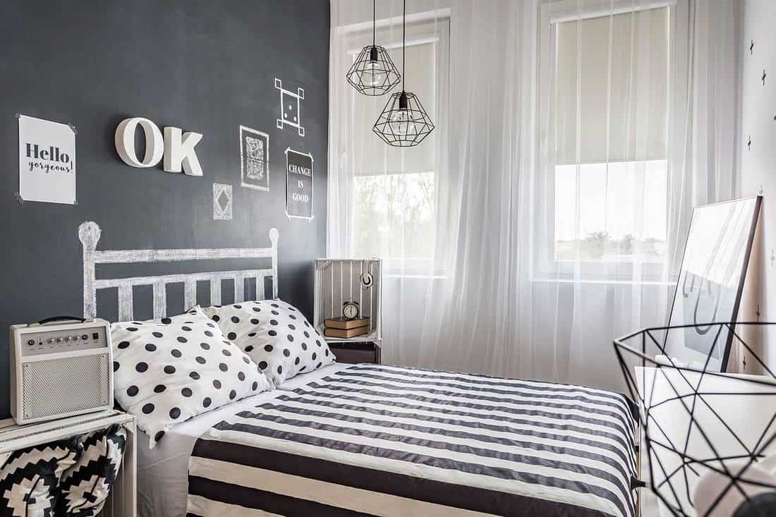 Shot of a small cozy black and white bedroom with white transparent curtains