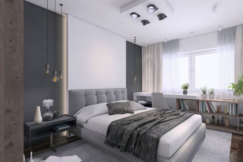 A luxurious bedroom with gray colored walls, gray beddings, and dangling lamps on the sides