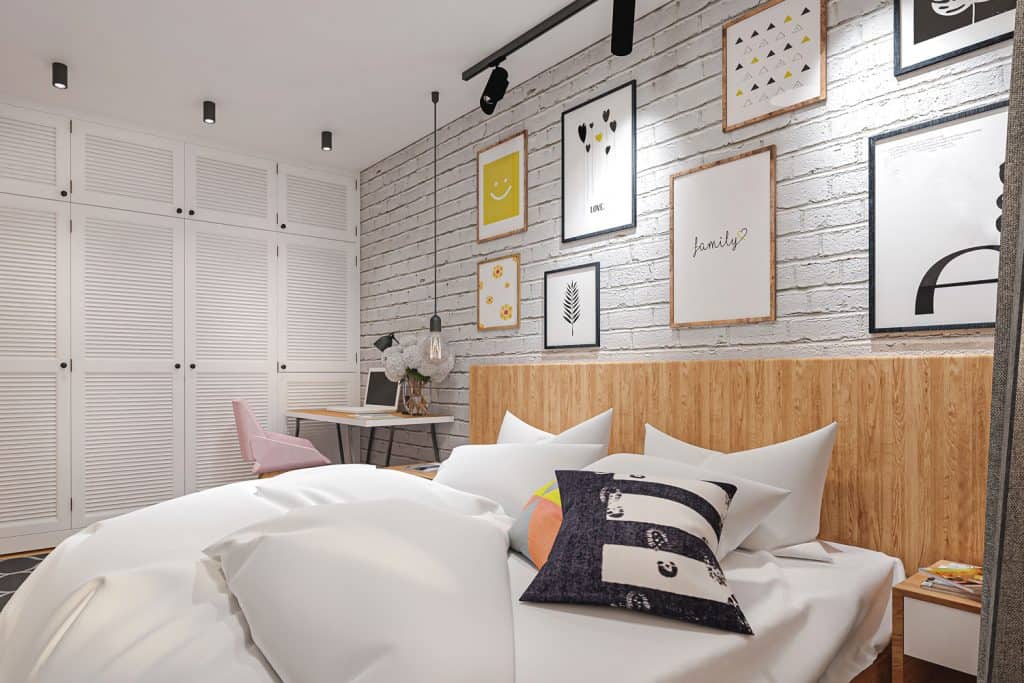 A small retro themed bedroom with pictures hanged on the wall and a white bed with white beddings with white pillows