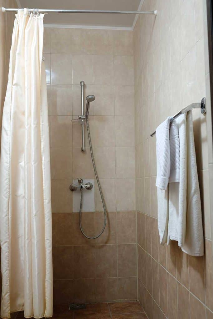 Douche de salle de bain avec murs carrelés et rideau de douche