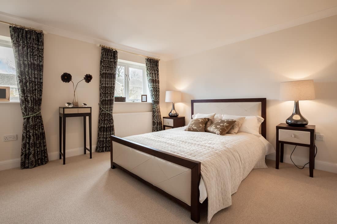 Staged luxury furnished bedroom within brand new home with matching bedspread and cushions 