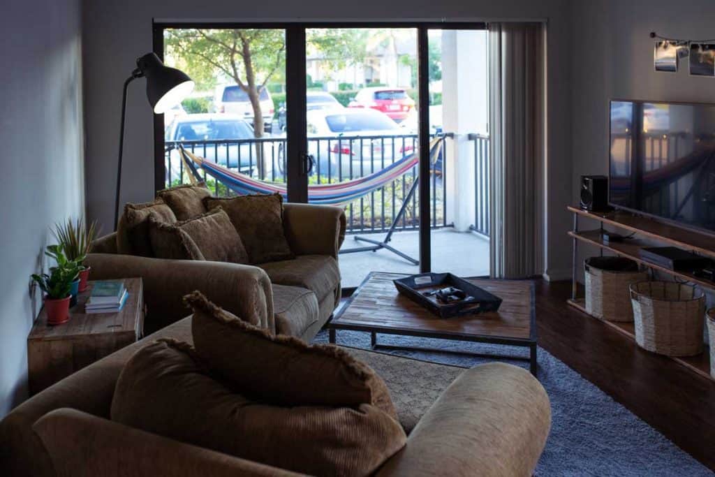 Modern living room with brown couches near window and hammock outside