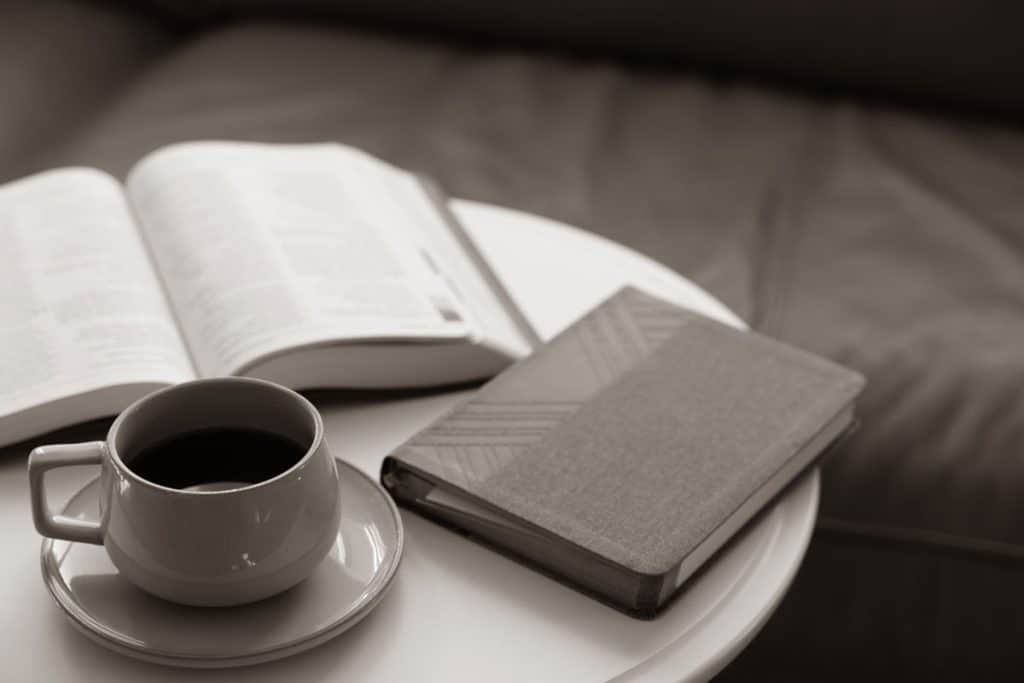 A book, coffee and a small notebook on the coffee table