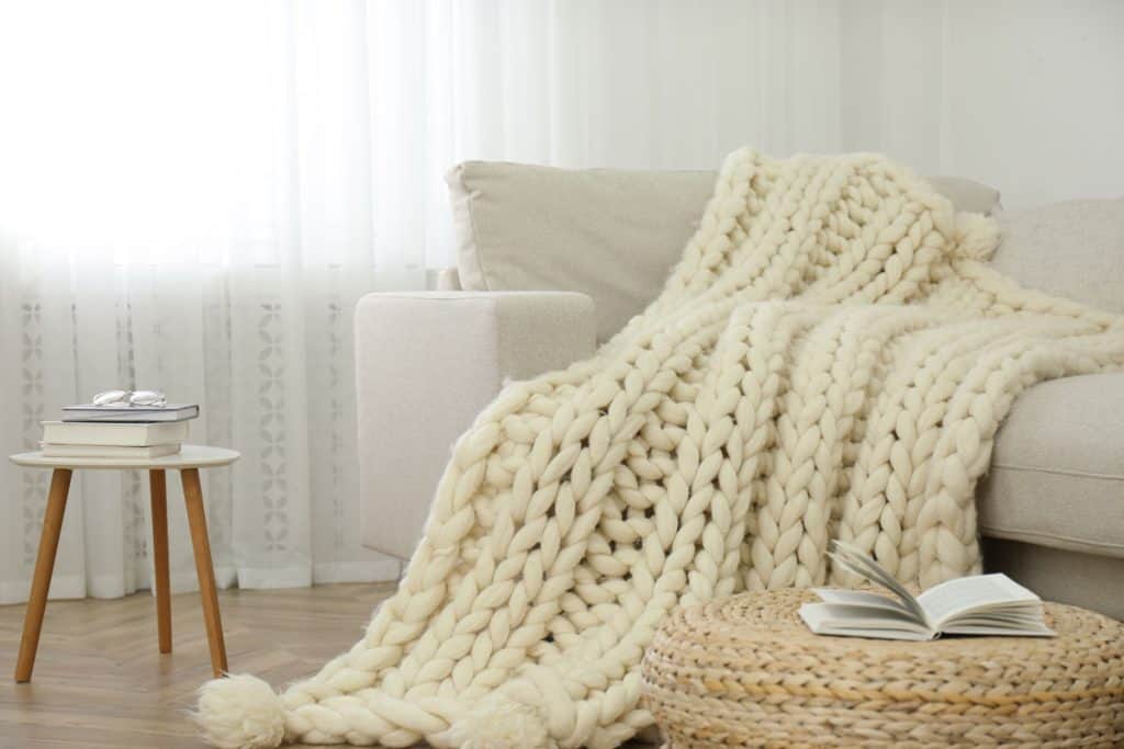 A gorgeous beige knitted blanket on the sofa