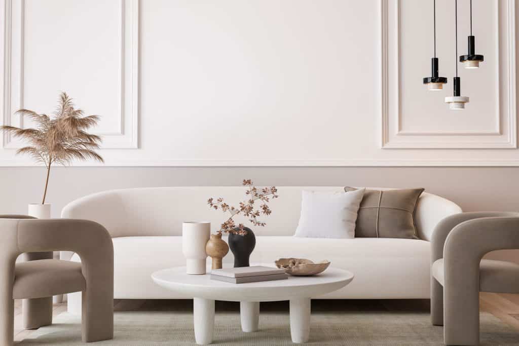 A white sofa with a matching white ceramic and wooden leg coffee table inside a white living room