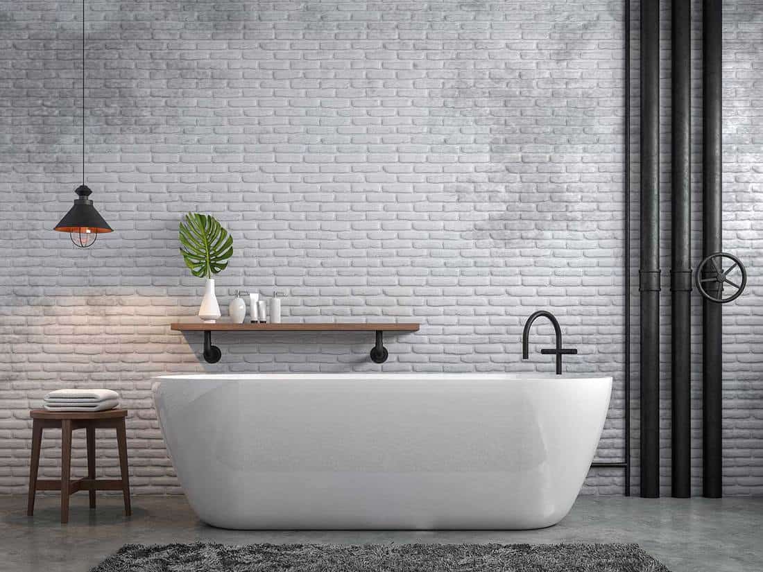 Salle de bain de style loft industriel avec mur de briques blanches et sol en béton ciré