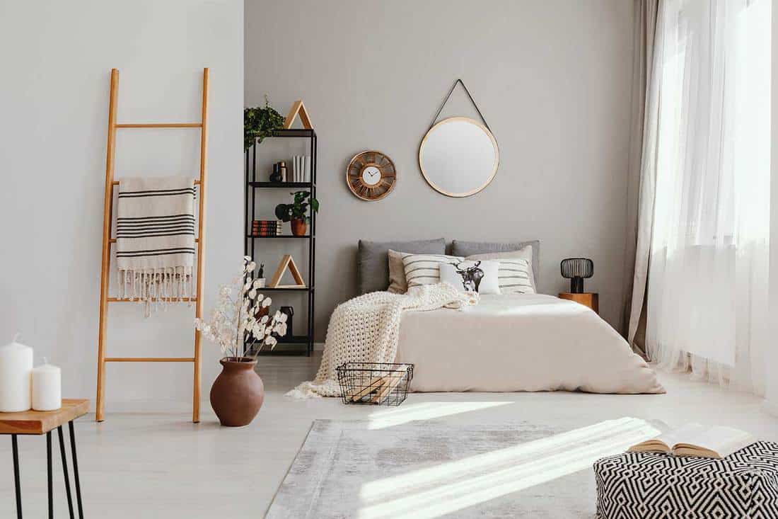 Minimalist scandinavian bedroom with clock, mirror, ladder and candles