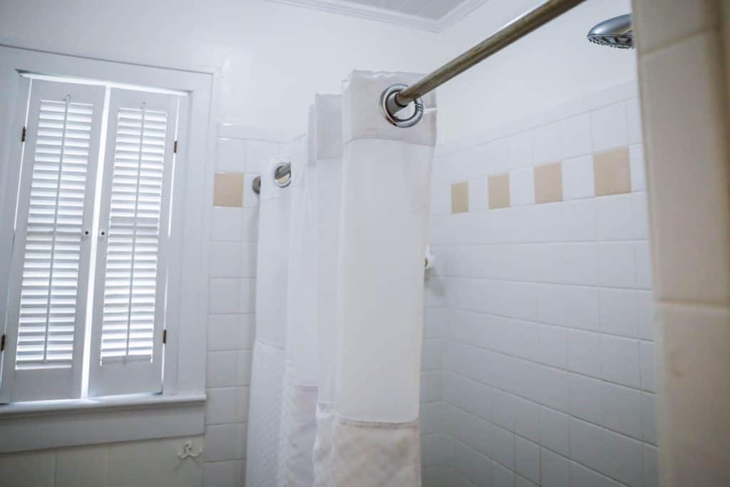 White shower curtains photographed in a narrow bathroom
