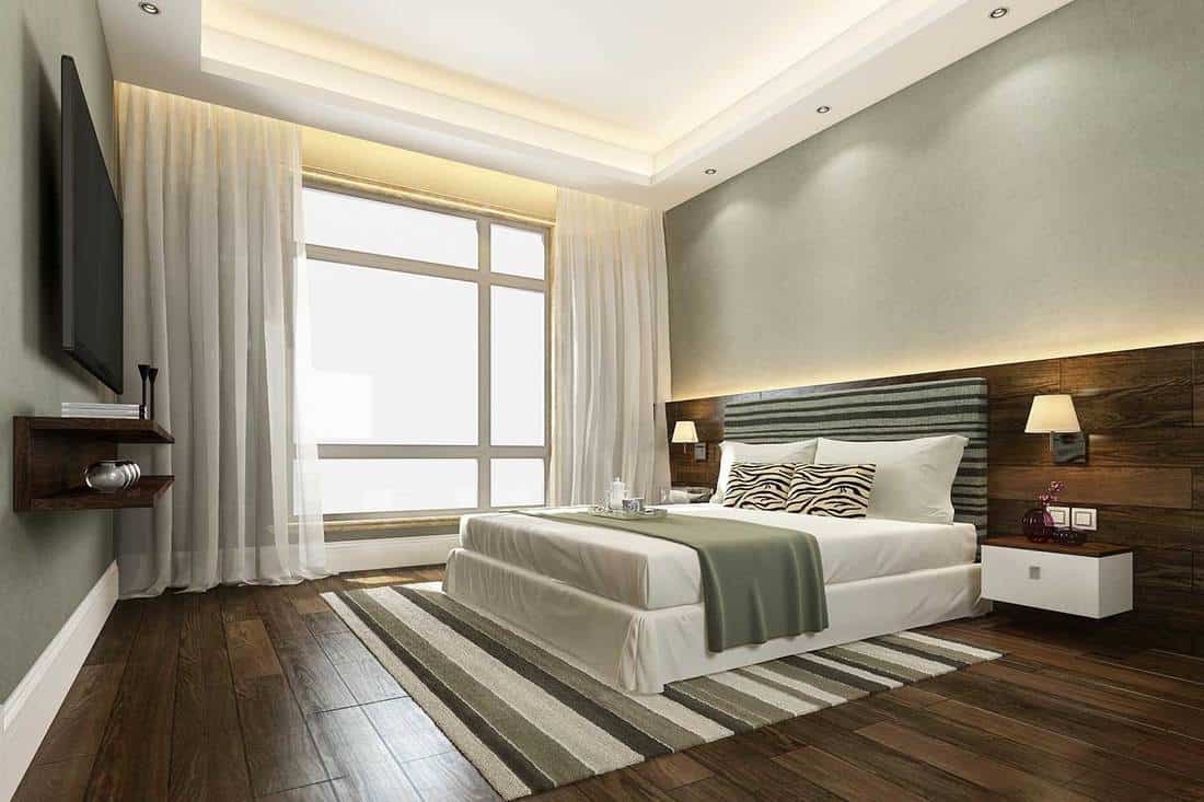 Beautiful white luxury bedroom suite in hotel with green blanket, hardwood floor and widescreen tv