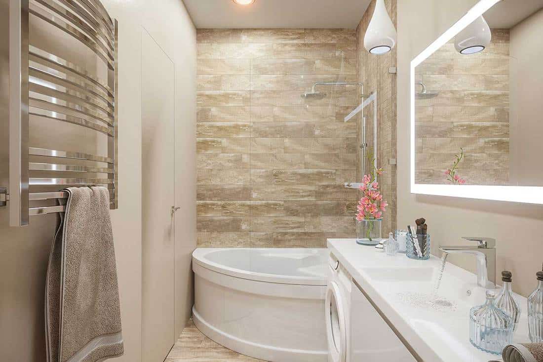 Interior of a bathroom in modern style with a corner bath, shower, large mirror and dryer in beige and white color