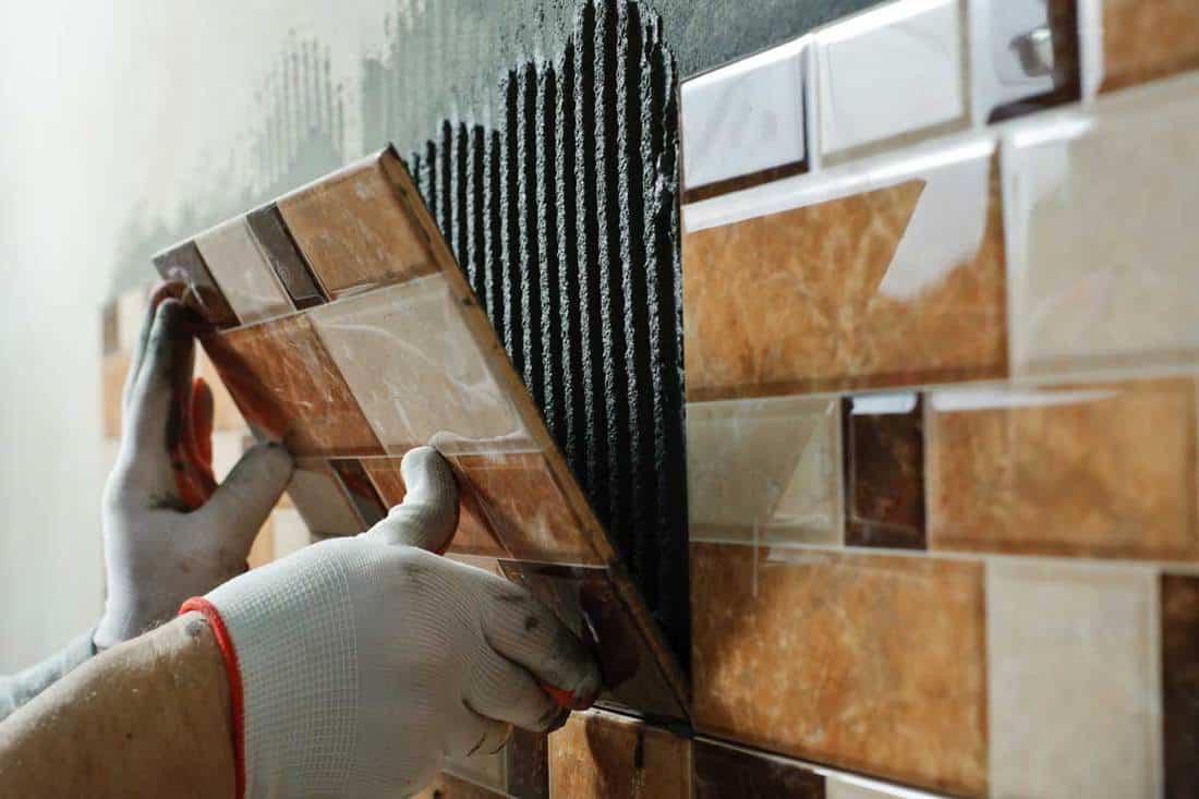 Laying-Ceramic-Tiles.-Tiler-placing-ceramic-wall-tile-in-position-over-adhesive