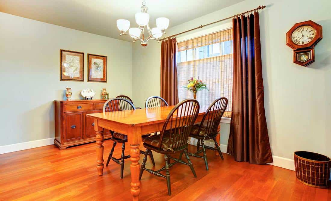 Light tones dining room with wood dining table set, rustic wall clock, wicker basket and storage cabinet