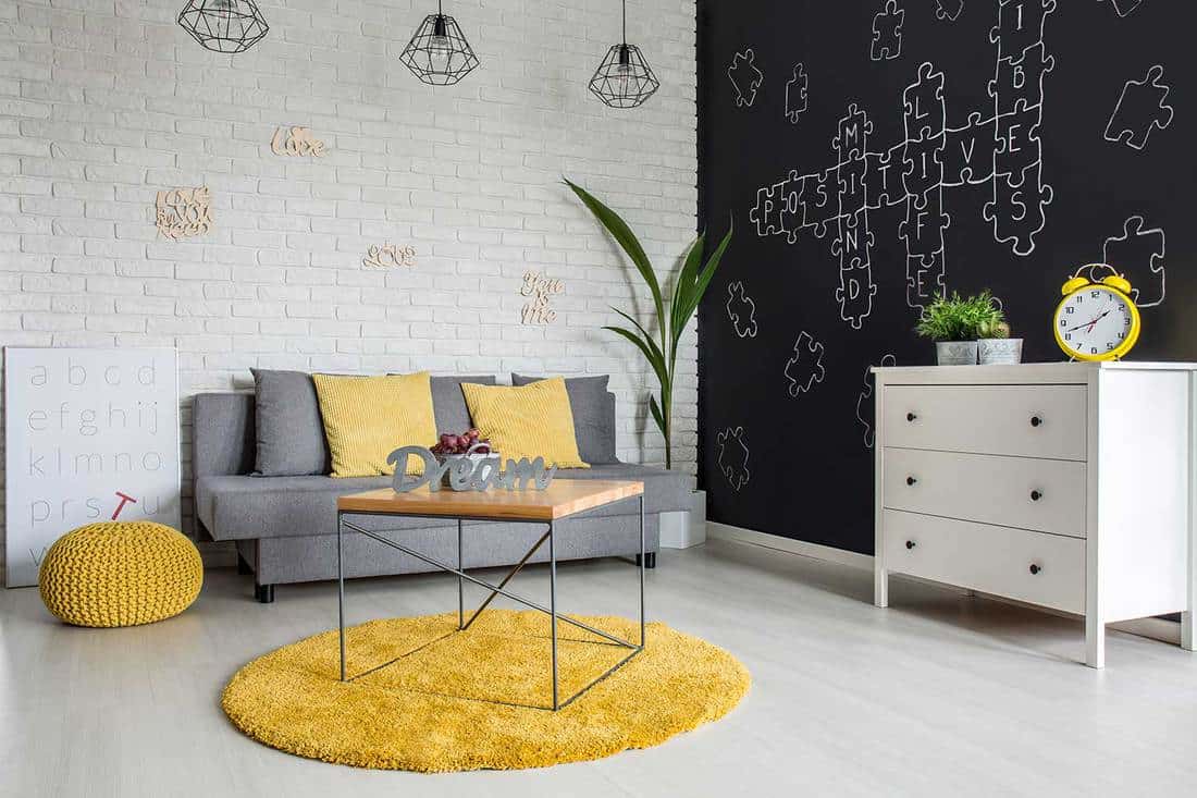 A cozy living room featuring a gray couch and a yellow rug, What Color Rug Goes With a Gray Couch
