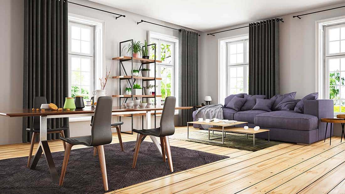 Modern loft room interior with cozy purple sofa, coffee and dining table