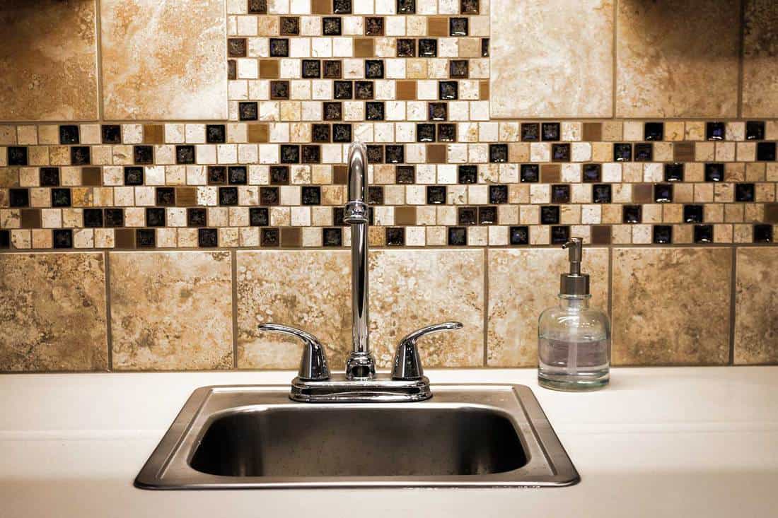 Small sink with faucet with brown mosaic tile backsplash