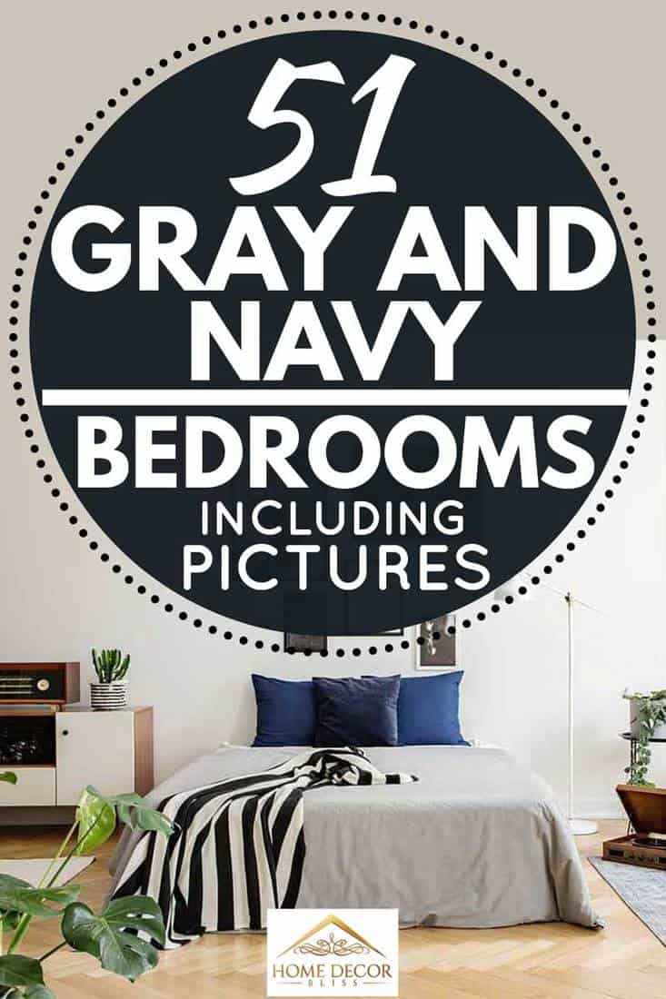 White wooden commode next to bed with dark bluepillows grey duvet and striped black and white blanket in bedroom with framed art gallery on the wall
