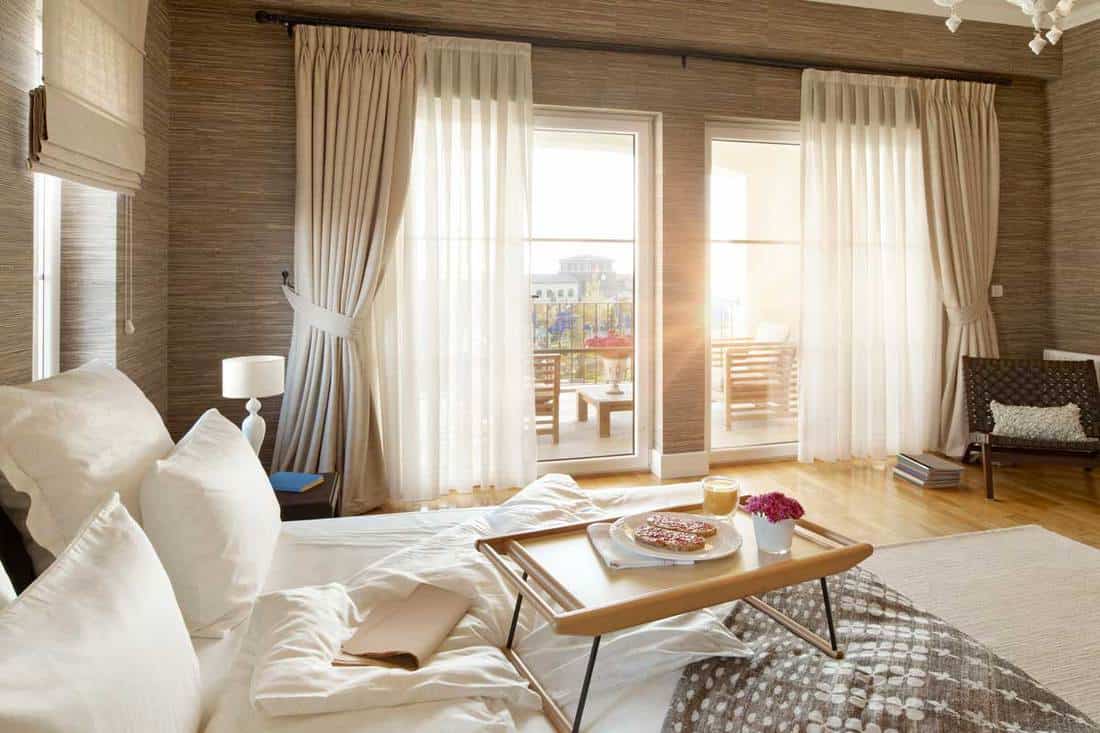 Brown color themed living room with white pillows and floor to ceiling high curtains