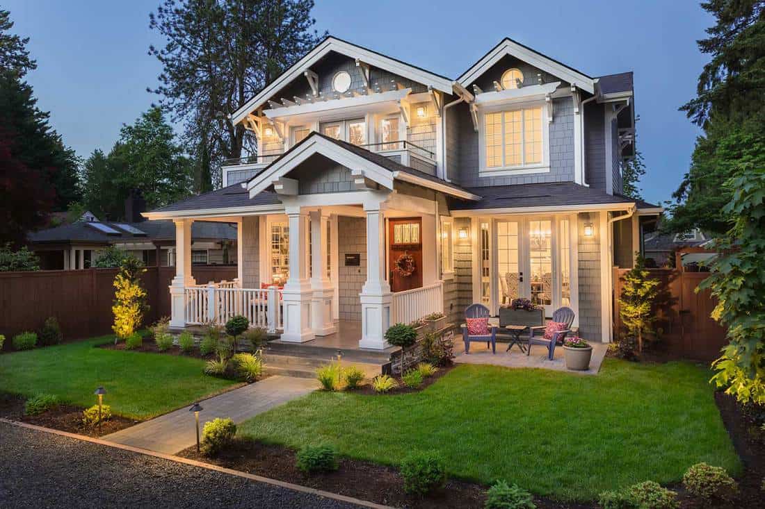 Façade d'une maison moderne avec pelouse bien entretenue, toile de fond d'arbres et allée menant au porche