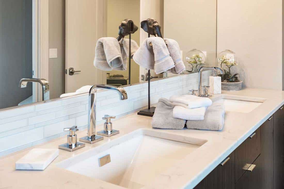 Luxury bathroom with double sink vanity, towels and hand sanitizer