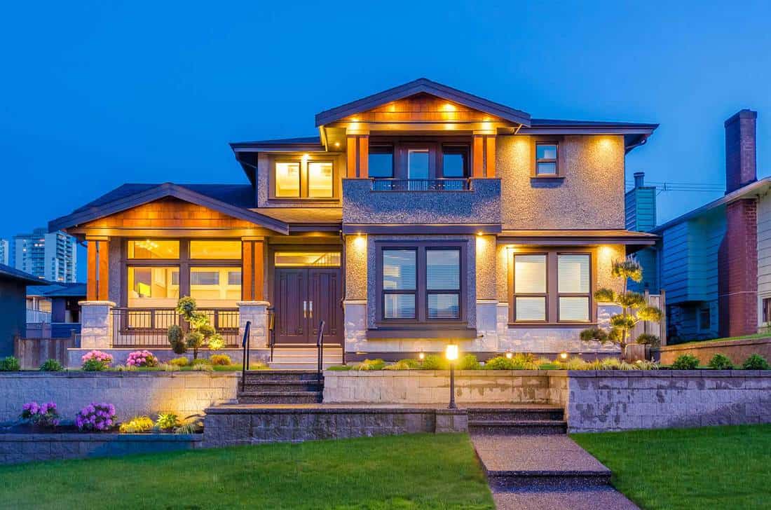 Maison de luxe la nuit avec porche, pelouse et escalier