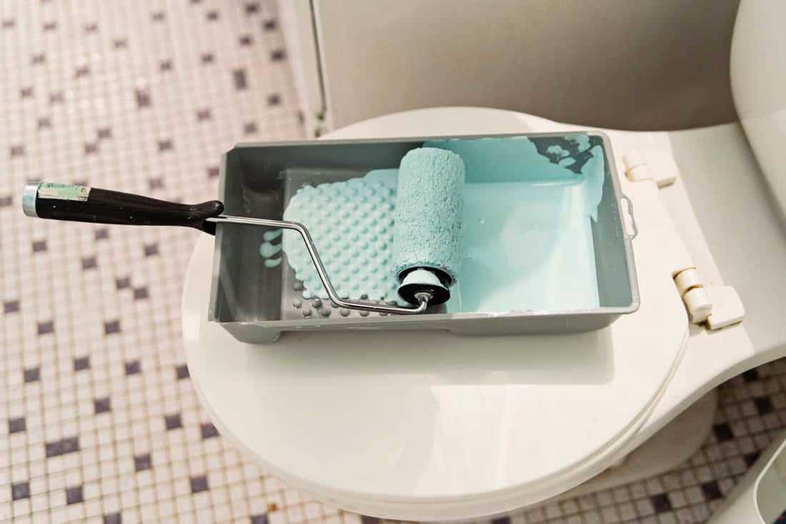Modern bathroom with paint roller on top of the toilet