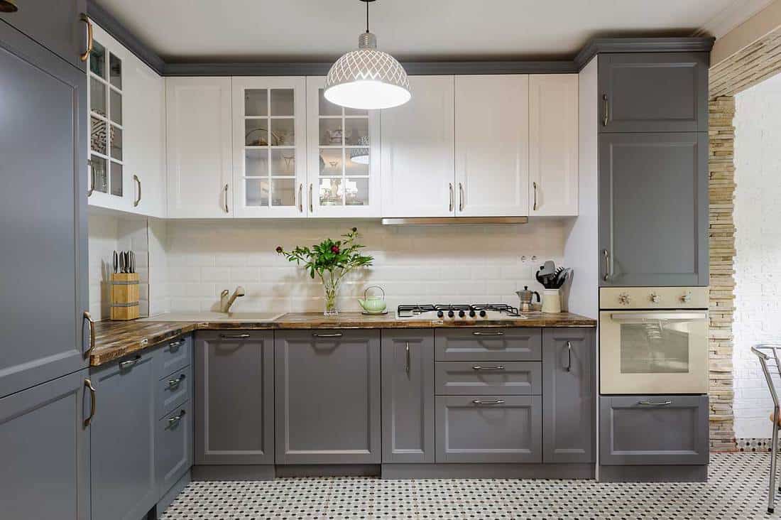 Interiore moderno della cucina in legno grigio e bianco con controsoffitto della cucina rustica e rose rosse sul vaso