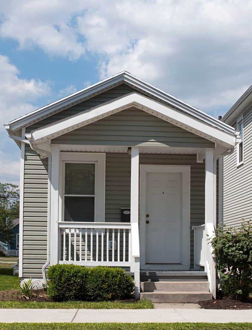 Tiny gray house with white door and front porch