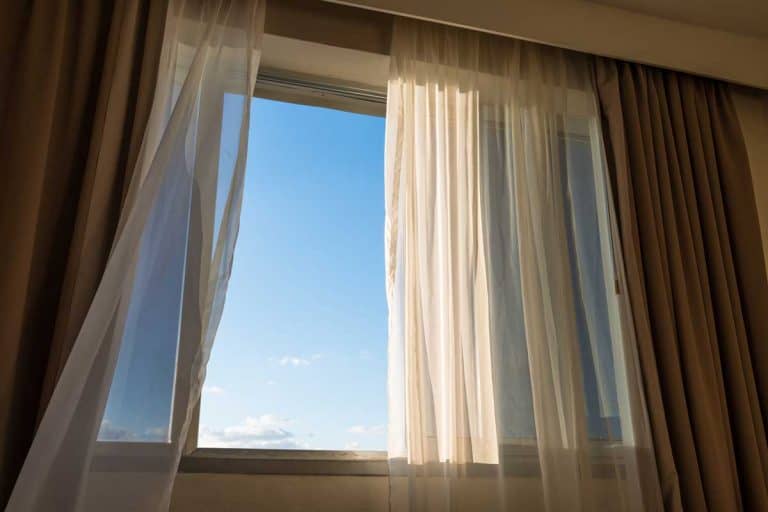 Waving curtains on window with view to blue sky